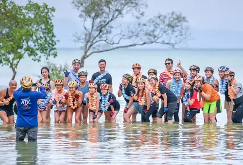 ATV tour group posing for a photo by the sea during Phuket ATV Adventure, featured by Phuket Travel Store