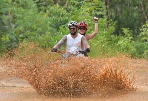 ATV rider splashing through muddy terrain at Phuket ATV Adventure, available from Phuket Travel Store