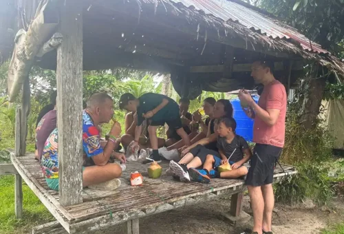 Cycling group resting in a traditional Thai sala in a quiet village on Koh Yao Noi, surrounded by greenery and rural charm.