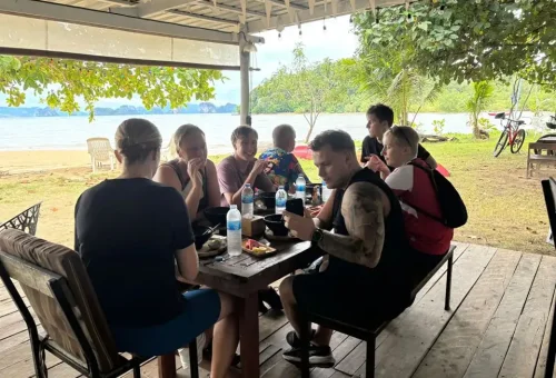 Cycling group enjoying lunch at a beachfront restaurant on Koh Yao Noi, with ocean views, tropical ambiance, and relaxed island vibes.