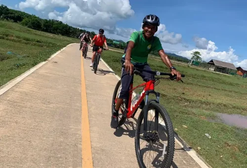 Friendly cycling guide standing with a mountain bike on a scenic trail at Koh Yao Noi, ready to lead the group through the island’s countryside.