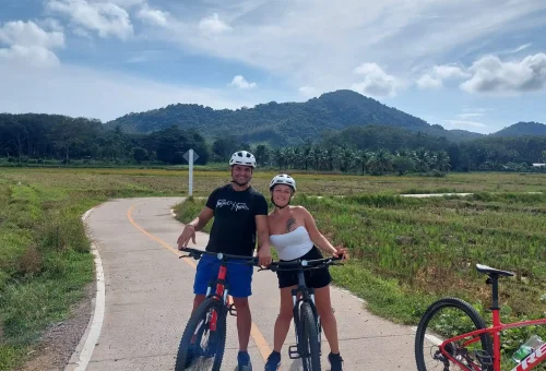 Cyclist pedaling along a quiet rural road through the heart of Koh Yao Noi, surrounded by tropical landscapes, palm trees, and traditional island life.