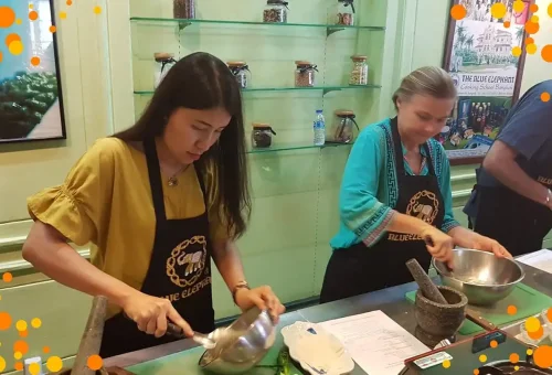 Student cooking in a professional Thai kitchen at Blue Elephant Cooking School in Phuket, wearing an apron and learning hands-on culinary techniques.