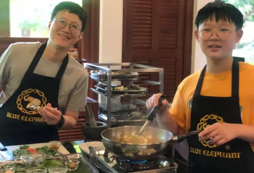 Group of cheerful Chinese students smiling and enjoying their Thai cooking experience at Blue Elephant Cooking School in Phuket.