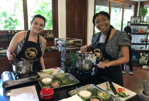 Group of cheerful students cooking together in the kitchen at Blue Elephant Cooking School Phuket, enjoying their hands-on culinary experience.