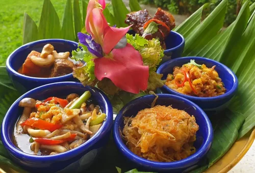 Colorful and perfectly plated Thai dishes prepared by students at Blue Elephant Cooking School in Phuket, displayed on a traditional serving table.