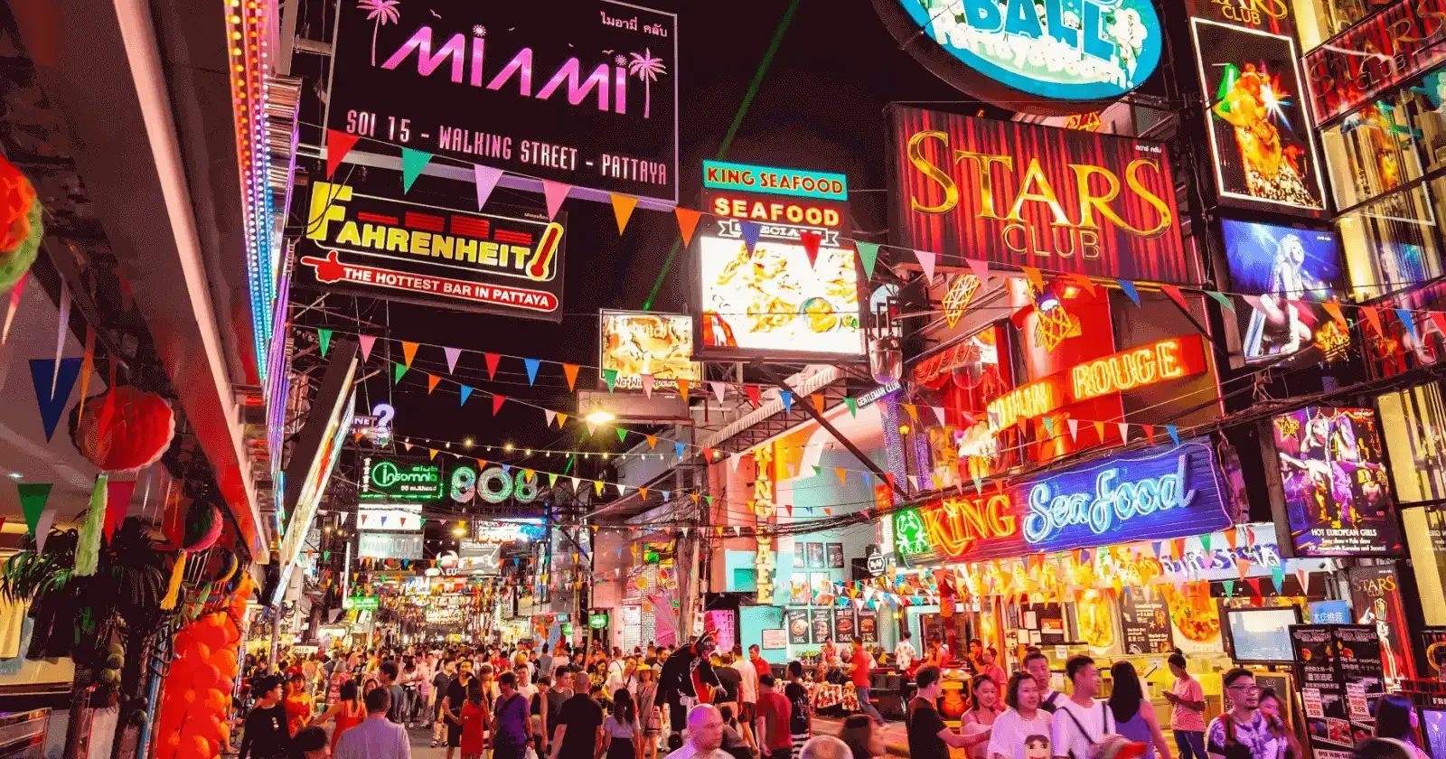 Vibrant nightlife scene in Thailand—neon lights, lively crowds, beach bars, and DJs creating an electric atmosphere, captured during a night out with Phuket Travel Store.