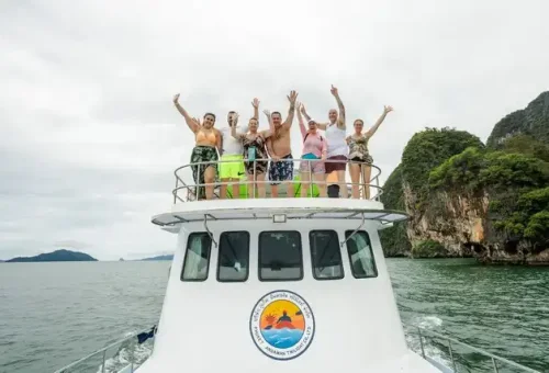 Smiling tourist enjoying the view from the deck of a large boat during the twilight sea canoe tour in Phang Nga Bay