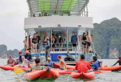 Scenic view of the main twilight sea canoe tour boat with multiple canoes exploring the surrounding waters in Phang Nga Bay