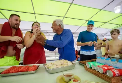Tour guide serving fresh tropical fruits and snacks to guests on board the twilight sea canoe tour boat in Phang Nga Bay
