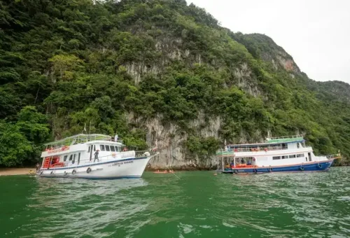 Multiple base tour boats anchored in Phang Nga Bay, ready to launch canoes for the twilight sea canoe excursion