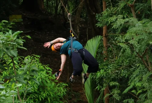 Excited zipliner mid-air above the treetops at Flying Hanuman, enjoying the thrill and scenic views of Phuket’s jungle