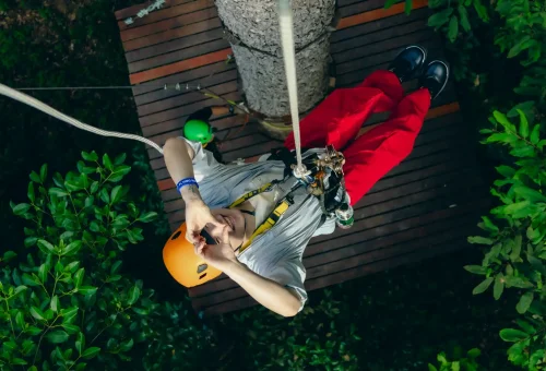 Adventurer zipping through the forest canopy on a thrilling ride at Flying Hanuman in Phuket, surrounded by lush greenery