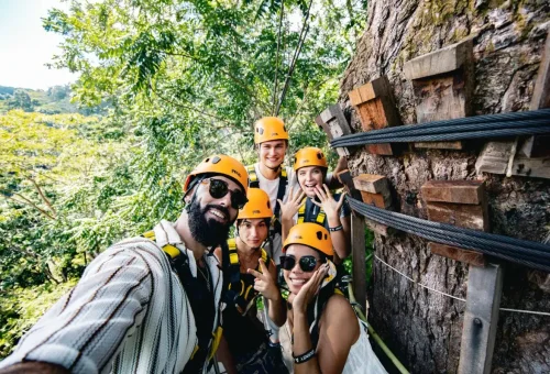 Thrill-seeker ziplining at a high altitude through dense jungle canopy at Flying Hanuman, Phuket