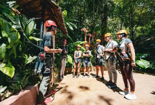 Guest gliding through the treetops on a zipline at Flying Hanuman, Phuket, with arms outstretched like an eagle in flight