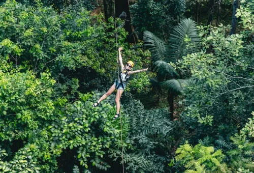 Couple and family members mid-zipline, smiling and enjoying the thrilling jungle ride at Flying Hanuman in Phuket
