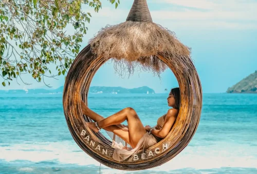 Wooden swing at the entrance of Banana Beach, Coral Island, with a “Welcome to Banana Beach” sign and tropical backdrop