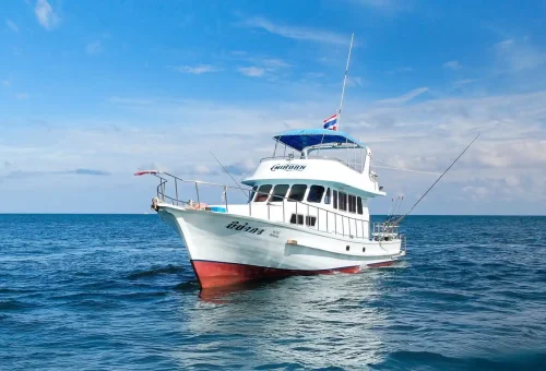 Fishing boat anchored in the blue waters off Phuket, equipped with rods and gear for game fishing and trolling