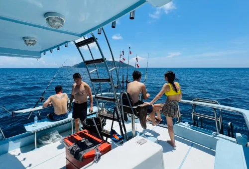 Smiling customers enjoying their time fishing on a trolling boat during a game fishing trip in the waters off Phuket