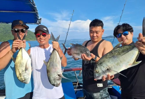 Smiling angler proudly showing off their fresh catch on a fishing boat during a game fishing and trolling trip in the waters around Phuket