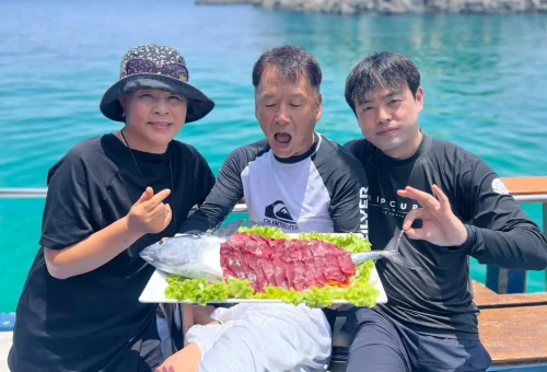 Excited customer holding up a large fish catch on a fishing boat during a trolling and game fishing trip in Phuket