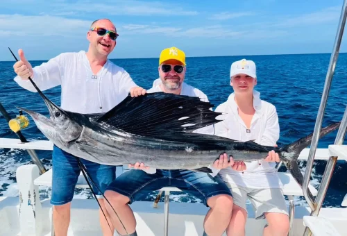 Happy angler showcasing their fish catch on a fishing boat during a game fishing and trolling tour in the waters off Phuket