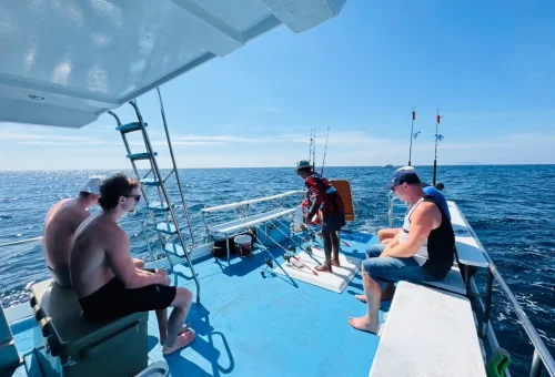 Happy group of customers fishing together on a trolling boat during a game fishing tour in the waters around Phuket
