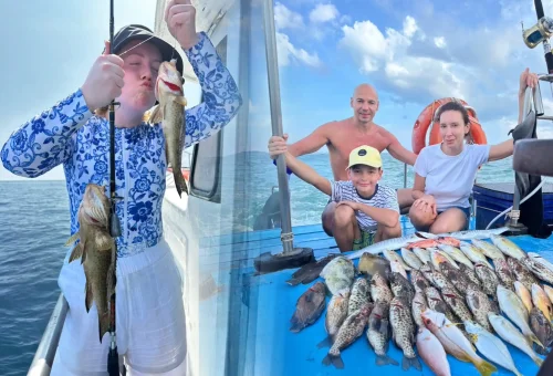 Smiling customer holding up a large fish proudly on a fishing boat during a game fishing and trolling tour in Phuket