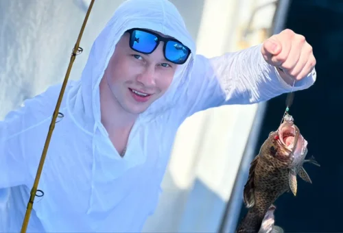 Excited customer proudly showing their freshly caught fish on a game fishing and trolling boat in the waters around Phuket