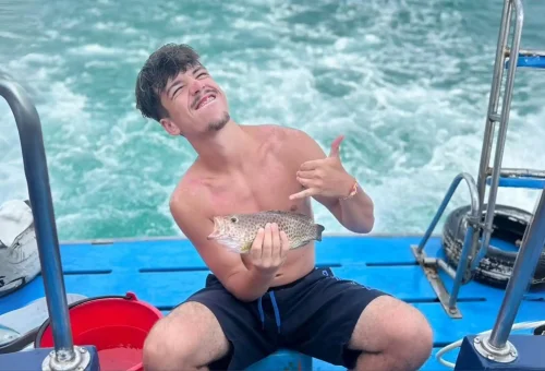 Happy fisherman proudly holding up a large fish on a game fishing and trolling boat off the coast of Phuket