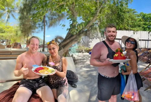 Colorful tray of fresh tropical fruits served on the sand at Kahung Beach, Coral Island, with sea views in the background