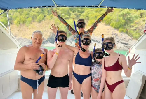 Happy traveler on a speedboat to Raya Island, wearing snorkel gear and excited for the snorkeling experience.