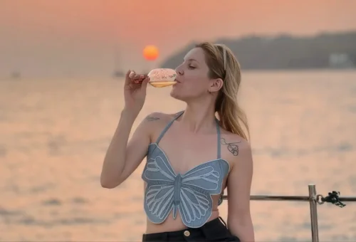 Guest relaxing with a glass of wine while watching the sunset on a sailing yacht near Coral Island and Promthep Cape.