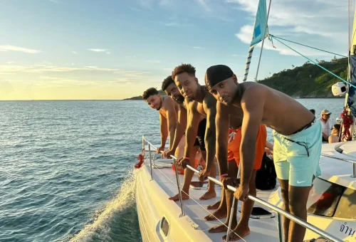 Four friends sitting on a yacht, enjoying the golden sunset near Coral Island and Promthep Cape.