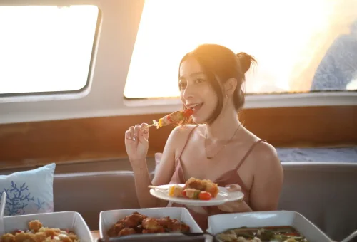 Guests enjoying a dinner buffet during sunset on a sailing yacht near Coral Island and Promthep Cape.