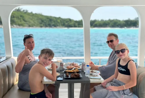 Group of happy travelers enjoying views and drinks aboard a luxury sailing cruise to Racha and Coral Islands in Phuket.