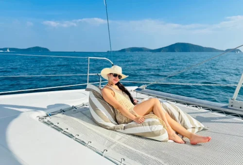 Happy travelers relaxing and taking selfies on a luxury sailing yacht with turquoise waters en route to Racha and Coral Islands, Phuket.