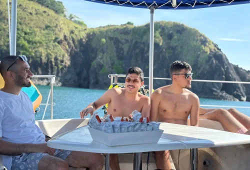 Excited passengers dancing and enjoying the party atmosphere on a luxury sailing yacht en route to Racha and Coral Islands in Phuket.