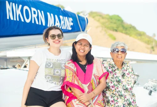 Joyful travelers enjoying the sunset and ocean breeze on the deck of a luxury sailing yacht to Racha and Coral Islands, Phuket.