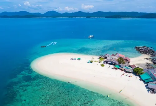 Aerial view of Khai Nai Island showing vibrant blue waters, white sandy shoreline, and tropical greenery from the Phi Phi Island speed catamaran tour with Phuket Travel Store