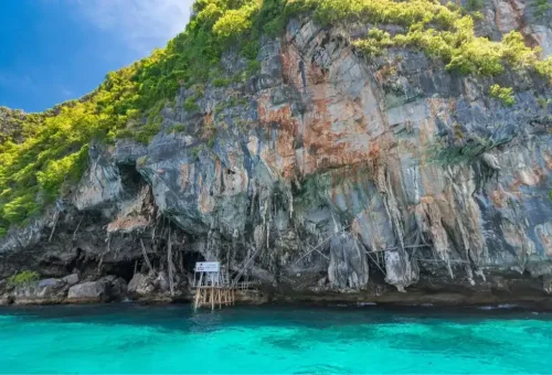 Viking Cave at Phi Phi Leh Island with rugged limestone cliffs and cave entrance above turquoise water, seen during the Phi Phi Island speed catamaran tour by Phuket Travel Store