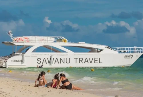 Speed catamaran docked on a sandy beach with clear turquoise water, part of the James Bond Island tour by Phuket Travel Store