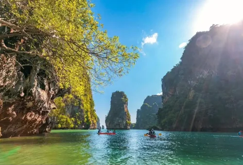 Guests canoeing through limestone caves and emerald-green waters at Hong Island, surrounded by dramatic cliffs during the James Bond Island tour