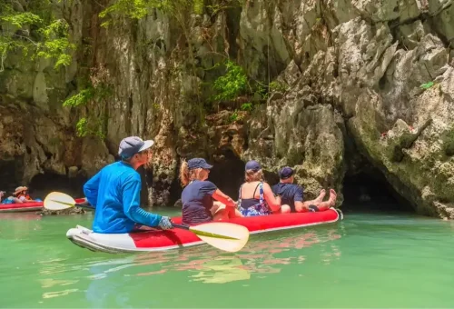 Canoe approaching a limestone cave at Hong Island, surrounded by emerald waters and towering cliffs, during the James Bond Island tour