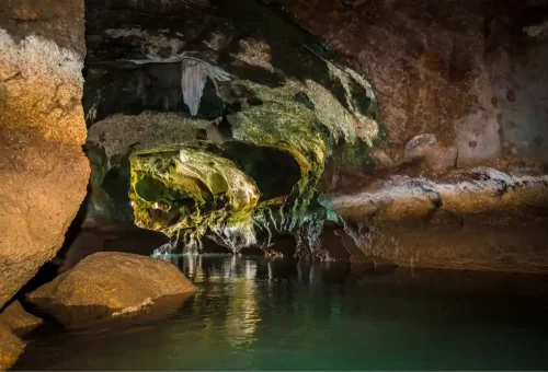 Canoe gliding through the dark interior of a limestone cave at Panak Island, with natural rock formations and calm waters on the James Bond Island tour
