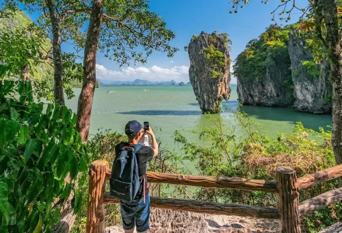 Tourist capturing a memorable photo of the iconic James Bond Rock in Phang Nga Bay, Thailand – PhuketTravelStore.com