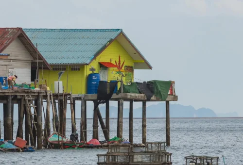 Scenic view of Koh Panyee village built on stilts above the sea, surrounded by limestone cliffs in Phang Nga Bay – PhuketTravelStore.com