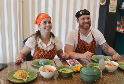 Smiling customer proudly holding Thai dish cooked at Kata Thai Cooking Class in Phuket