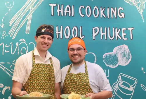 Happy customer holding their self-cooked Thai dish at Kata Thai Cooking Class in Phuket