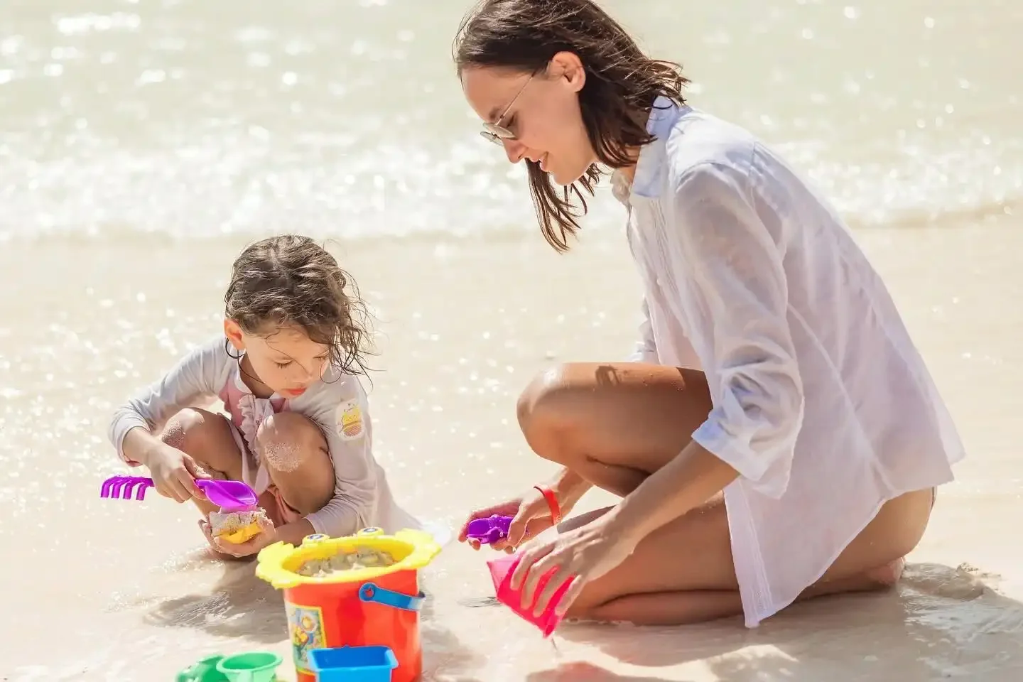 Mother and daughter playing together on the white sandy beach of Khai Island, enjoying a family moment in Phuket